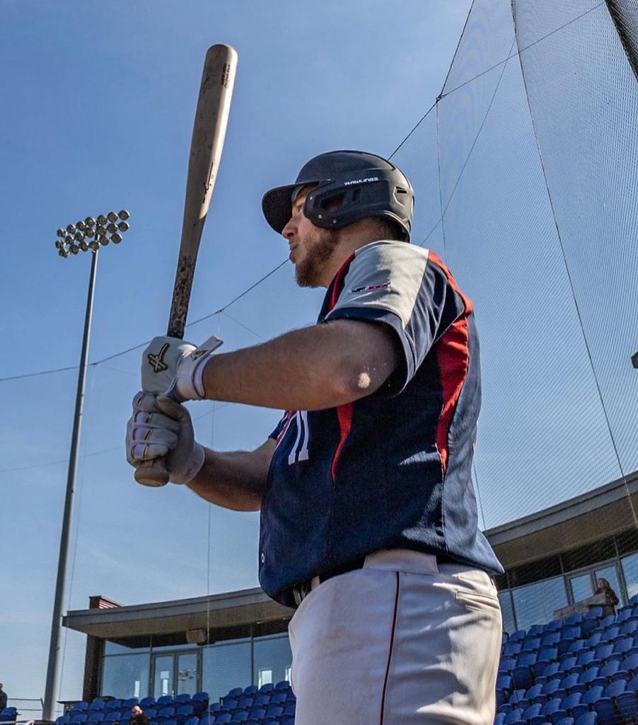 Aaron Isenia holding a hc bat and wearing hc batting gloves
