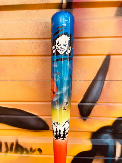Side view of the HC Bats CJ5 Fright Night baseball bat displaying detailed Halloween artwork with a glowing sunset, flying birds, spooky illustrations and a vibrant blue barrel.