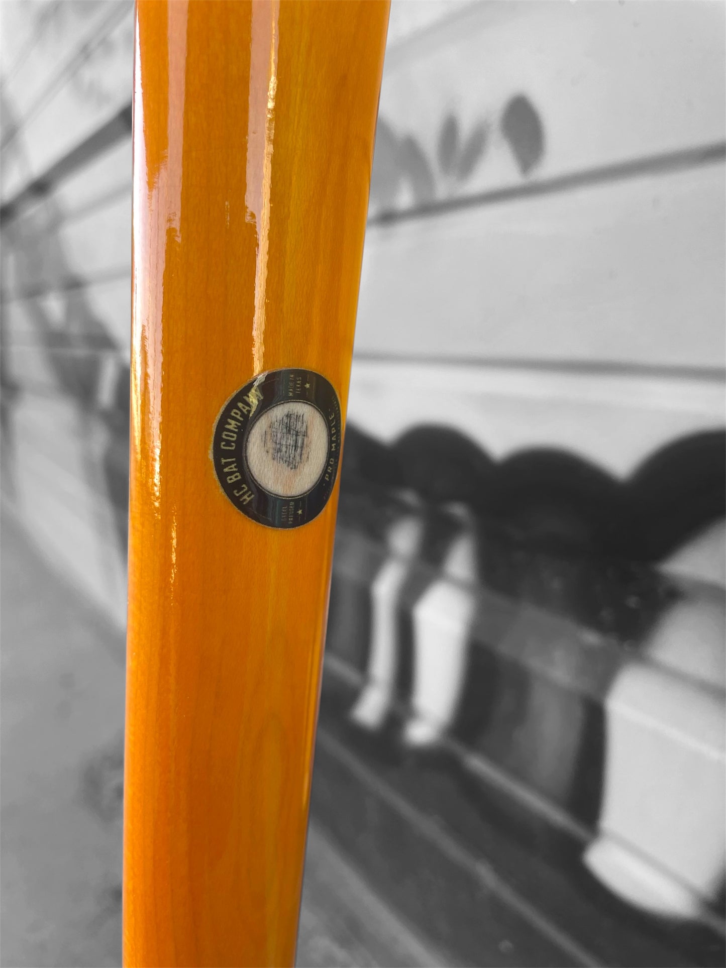 Close-up of the orange handle and natural maple transition on the HC 271HB baseball bat showing the ink dot and model markings.