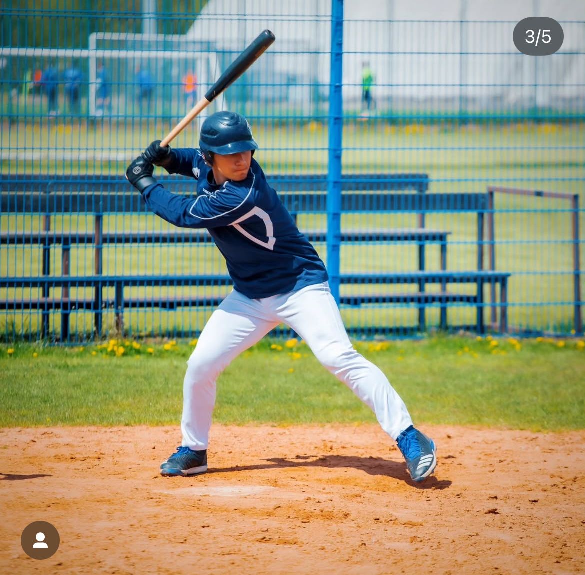 Ilya Sladzinski in batting stance on a field with blue dugout in background