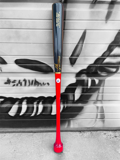 HC Bats CJ5 33.5-inch Pro Grade Maple baseball bat with red handle, hockey puck knob and dark navy-black barrel standing upright in front of a black and white graffiti wall.