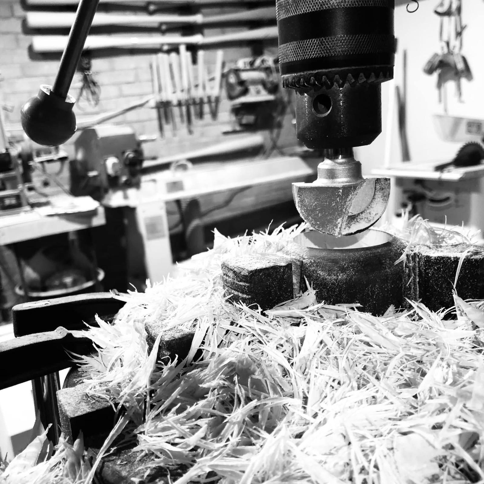Close-up of a drill bit being sharpened on a machine with shavings around.